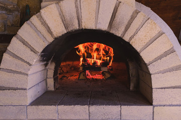 Wood fire burning inside a pizza oven with archway 