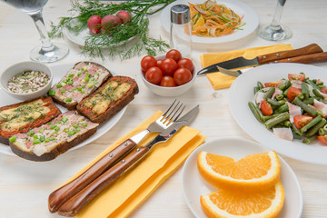 Waiting for lunch. Prepared salads of green beans, tomatoes, carrots, sandwiches with bacon cheese and herbs. Vitamin healthy snacks from cherry tomatoes, radishes, orange and cereals