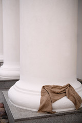 on a white concrete column lies a woolen scarf made of brown yarn, textured and with patterns