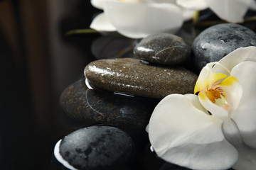 Spa stones and orchid flowers in water on black background, closeup. Zen lifestyle