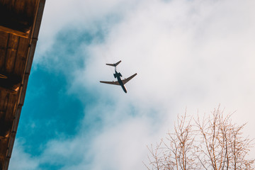 Plane flies at low altitude above the house. airplane in blue sky.