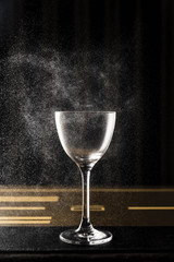 Spraying some aromatic oils across an empty nick and nora cocktail glass