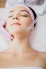 Girl receiving darsonval procedure electric massage at beauty salon. Hardware cosmetology. Selective focus.