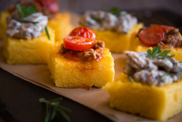 Slices of fried polenta with mushrooms and tomato sauce