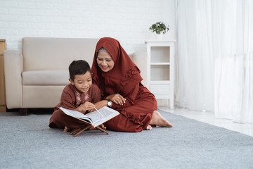 Asian boy learns the Al-Quran with her mother at home