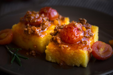 Slices of fried polenta with meat and tomato sauce