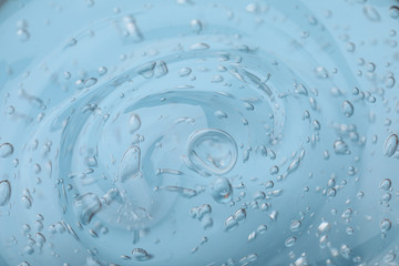 Pure transparent cosmetic gel on light blue background, closeup