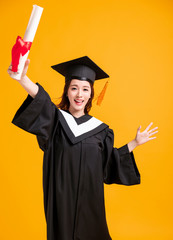 happy young woman in graduation gowns and showing the diploma