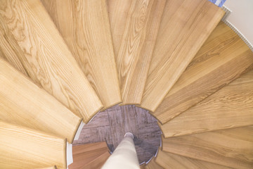 Spiral staircase with wooden steps on a metal base. View from top to bottom.