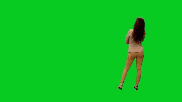 Rear view of young woman looking at exhibit objects in museum exhibition on green screen 