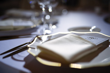 evening dim light on the festive table, a beautiful plate with a napkin and a menu in the...
