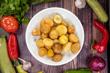 Tasty sauteed potatoes with garlic and spices on a plate, top view