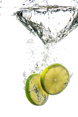 whole and sliced green lime falling under water with a splash and bubbles on a white or black background
