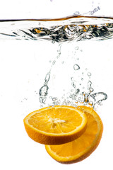 Fototapeta na wymiar whole and sliced orange falling under water with a splash and bubbles on a white or black background