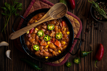 Chilly beans with hot pepper on dark wooden background