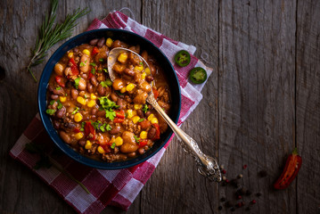 Chilly beans with hot pepper on dark wooden background