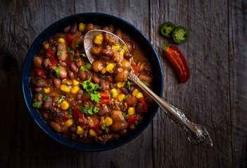 Chilly beans with hot pepper on dark wooden background
