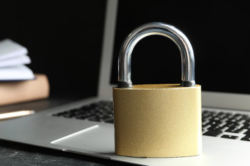 Metal lock and laptop on grey table, closeup. Protection from cyber attack