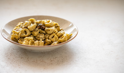 Tortellini al pesto over dotted plate closeup
