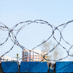 Barbed wire on a blurred background of a fragment of residential buildings. Concept of isolation. Selective focus.