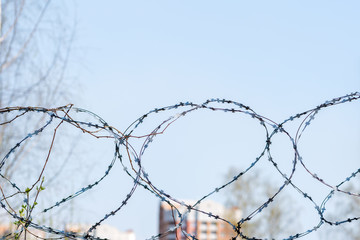 Barbed wire on a blurred background of a fragment of residential buildings. Concept of isolation. Selective focus.