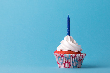 Cupcake with frosting and blue candle on blue background, red, white and blue, copy space
