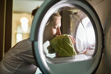 Frau riecht saubere Wäsche aus Waschmaschine