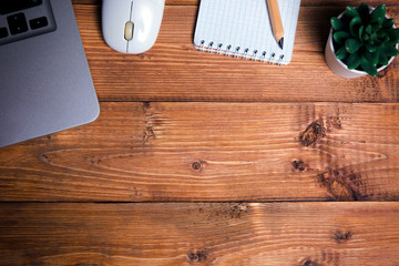 Wooden desktop, laptop, wireless mouse, notebook and flower
