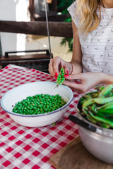 Woman preparing fresh organic peas and taking it out from a shell.