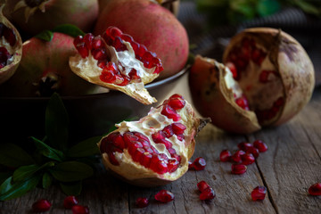Fresh organic pomegranate fruit with leaves on dark background