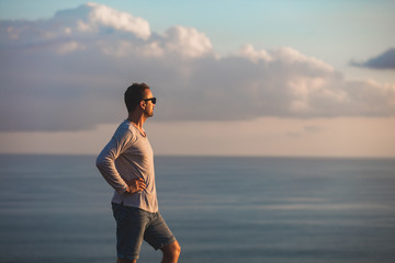 Man with nice tropical summertime sunset on the island above the ocean.
