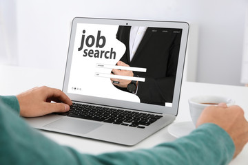 Man searching job with laptop at table, closeup