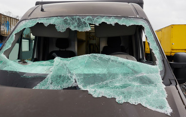 Smashed windshield by vandalism on a brown courier truck wreck, abandoned for scrapps.