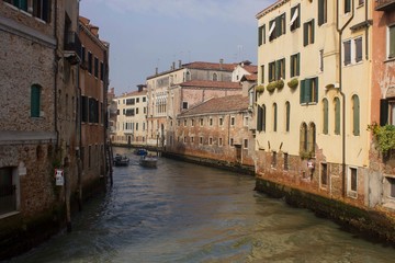 Traditional canal in Venice with motoboat crossing it
