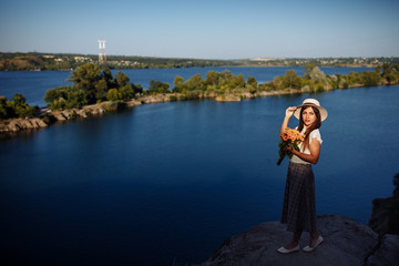 girl in a long dress with flowers on the background of a career lake