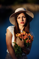 girl in a long dress with flowers on the background of a career lake