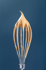 Metal balloon whisk with whipping instant coffee foam for dalgona drink, vertical