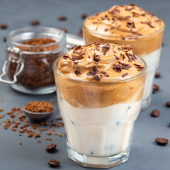 Dalgona coffee with ice garnished with grated chocolate, trendy korean drink on a dark gray background, square