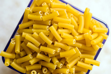raw italian macaroni pasta inside clear storage container