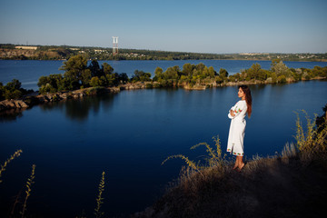 Fototapeta na wymiar girl in a long dress on a background of water, lake career