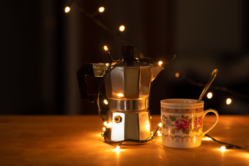 Máquina de café y taza con cuchara sobre una mesa de madera de restaurante iluminada