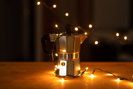 Peque&ntilde;a maquina de caf&eacute; plateada puesta sobre la mesa decorada con luces amarillas