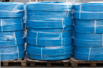 Blue plastic pipes folded into rolls. Production and sale of plastic pipes.