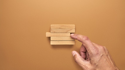 Męska dłoń i drewniane klocki ułożone w konceptualnym wizerunku © piotrszczepanek