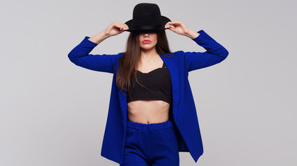 Positive brunette with a hat, trendy and modern girl in a dark blue suit