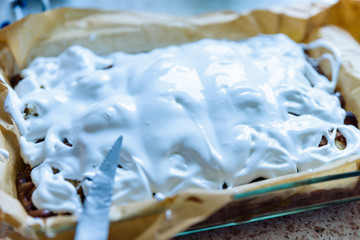 homemade fresh apple pie covered with white icing in baking tray with baking paper in it