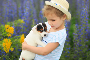 little girls with puppy in a field with purple flowers