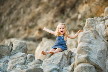 little girl sitting on rock at sunset. travel.