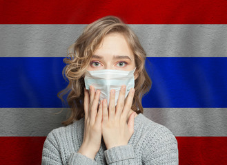 Scared woman in medical mask on Thai flag background. Flu epidemic and domestic violence concept