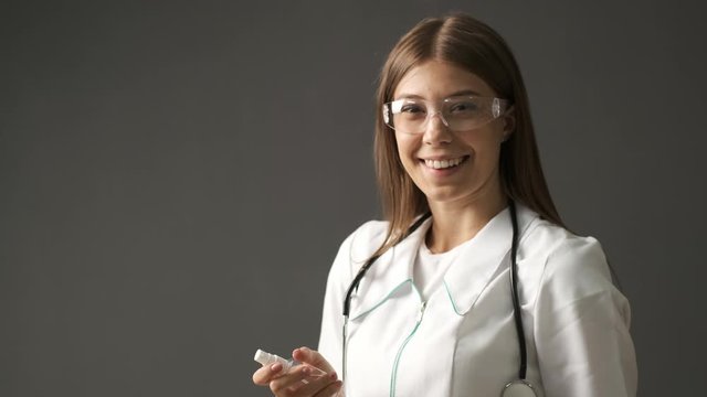 Doctor is a girl of Caucasian appearance holding an antiseptic in her hands and applying it on her hands